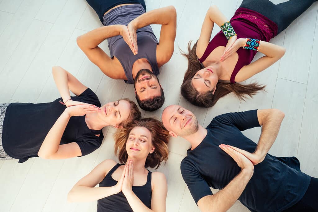 a happy group of people from men and women practicing yoga in the studio. groups of meditation , communication yoga class. the concept of group meditation and teamwork. coach and students in a circle