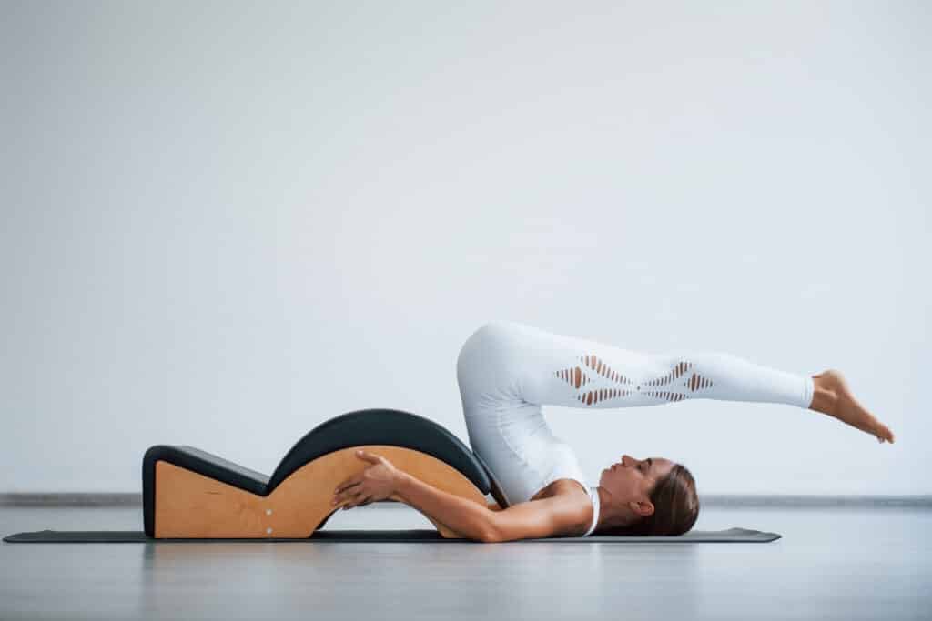 Good endurance needed. Confident young sporty woman with slim body type in the healthy center doing exercises by using special equipment