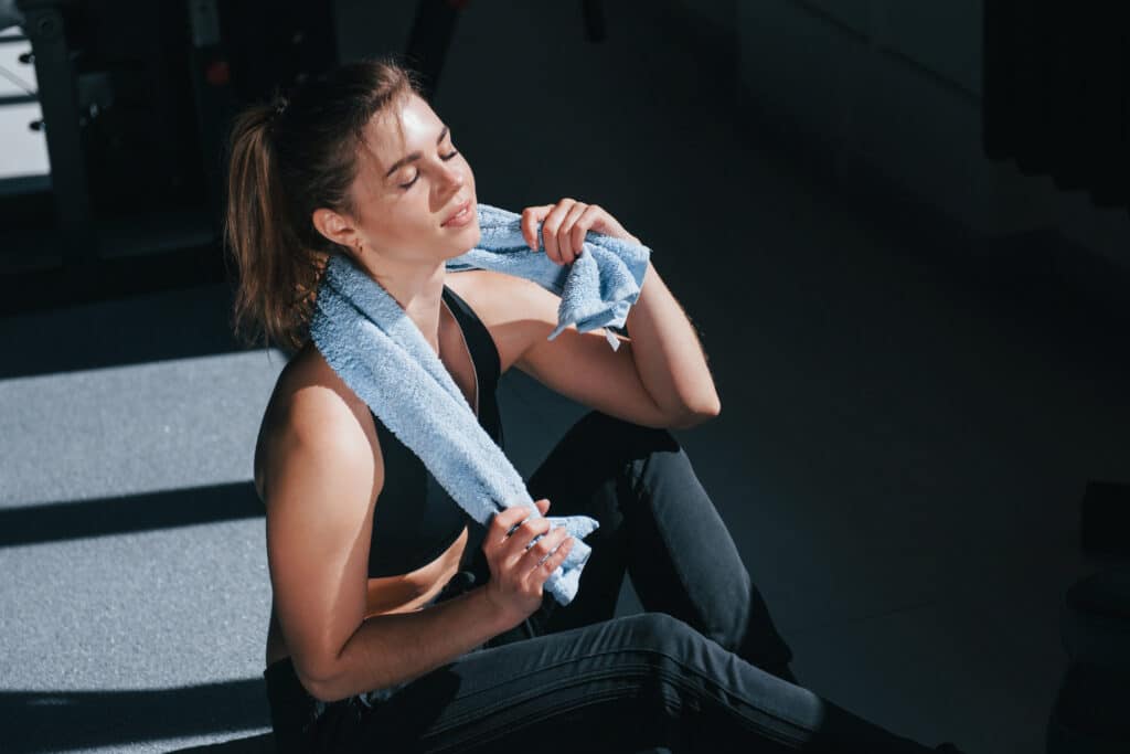 Sweating after workout. Photo of gorgeous blonde woman in the gym at her weekend time Sweating after workout. Photo of gorgeous blonde woman in the gym at her weekend time