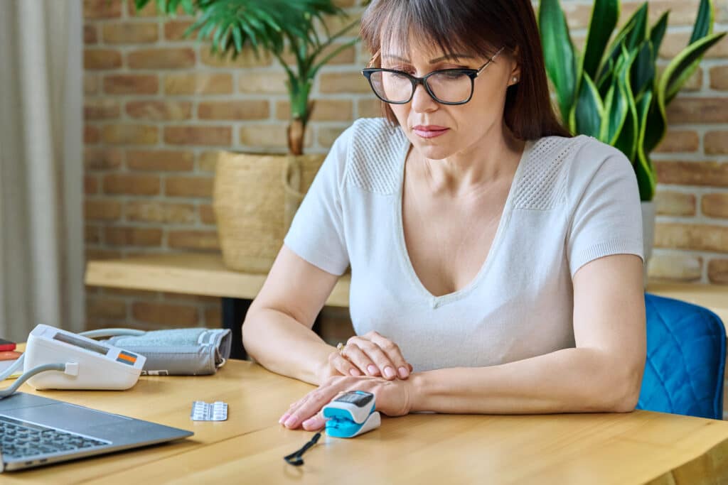 Middle-aged woman measuring level of oxygen in blood using pulse oximeter