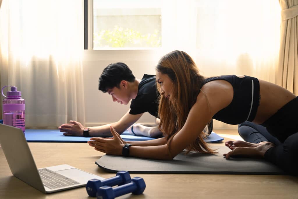 Young couple watching fitness lessons online on computer laptop