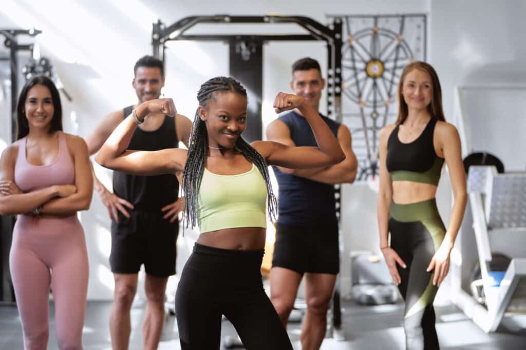 African fitness woman posing with biceps with a group of fitness people of different ethnicities.