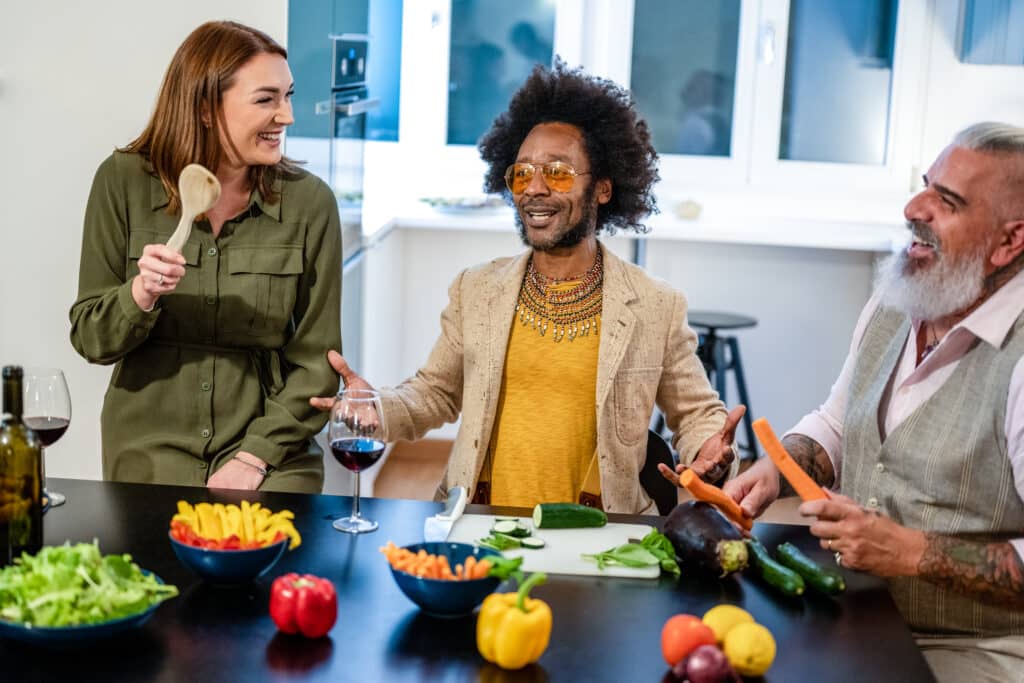 Happy adult friends cooking and preparing vegan dinner, people h