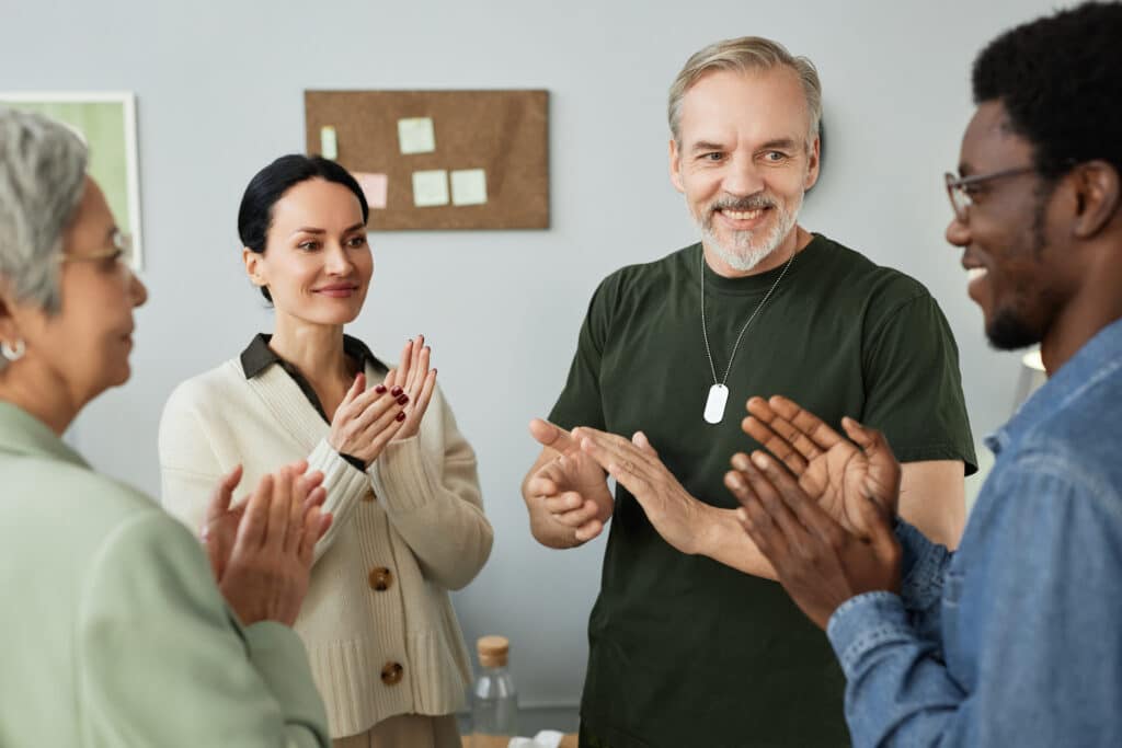 Group of happy intercultural people applauding to one of patients