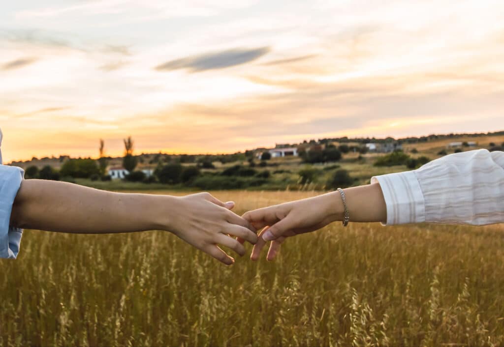 holding hands in a bautiful field at sunset