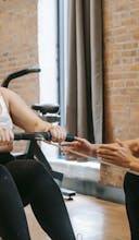 Focused young Asian male trainer helping overweight woman to do pulling exercise