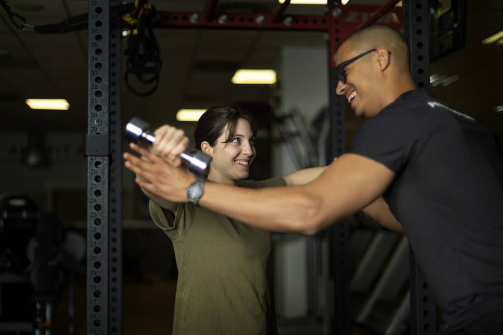 Woman and trainer share a laugh during gym dumbbell training session Woman and trainer share a laugh during gym dumbbell training session