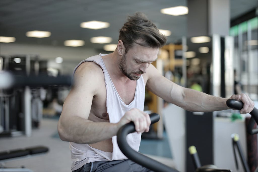 Tabata Ride: A High-Intensity Workout for Maximum Results Exhausted male athlete with muscles training on exercise machine and working on endurance in modern sports center