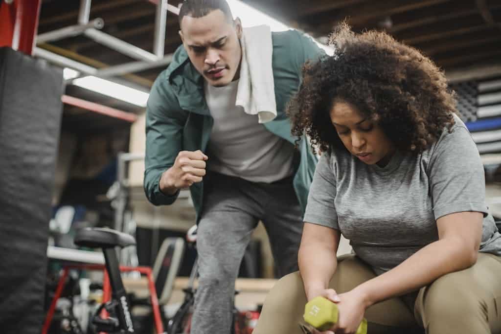 How to workout the right way: From Preparations to Recovery From below of strong personal coach explaining black woman how to exercise with dumbbells properly