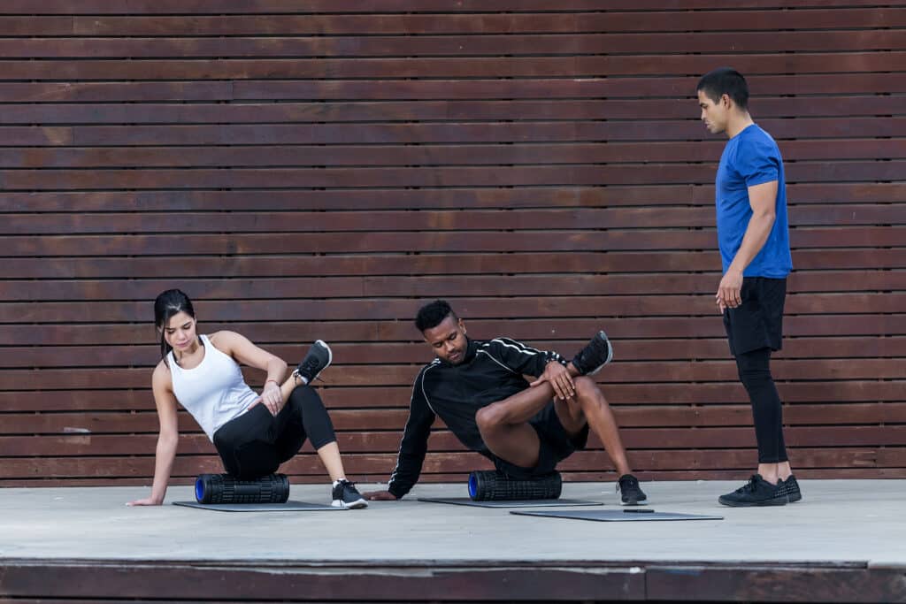 Trainer looking at athletes exercising on roller