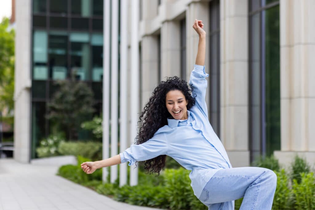 Joyful woman in casual clothes dancing outdoors expressing freedom