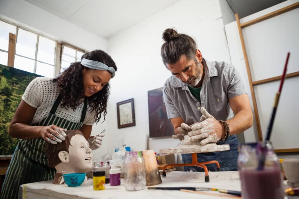 Attentive woman and man learning pottery in class