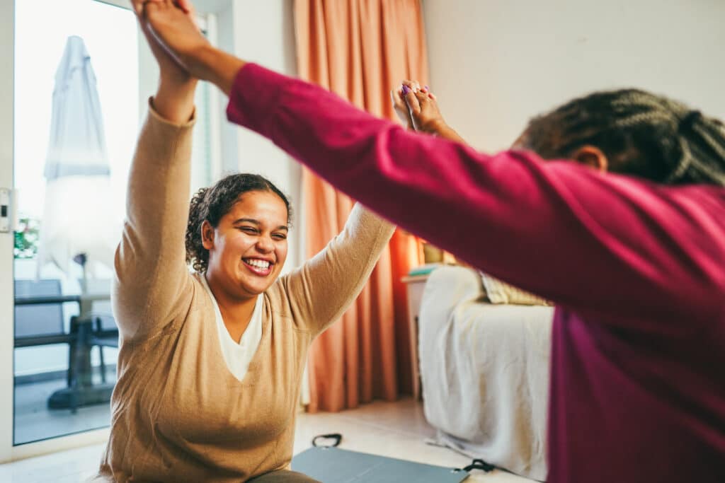 Mother and daughter doing fitness exercises at home together - F