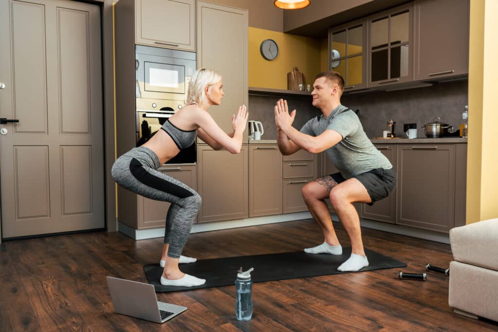 young couple practicing online yoga together on laptop at home during quarantine