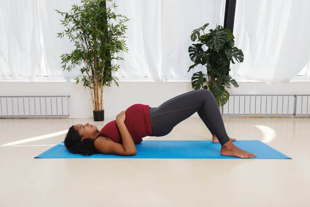 Pregnant young woman exercising on yoga mat in studio
