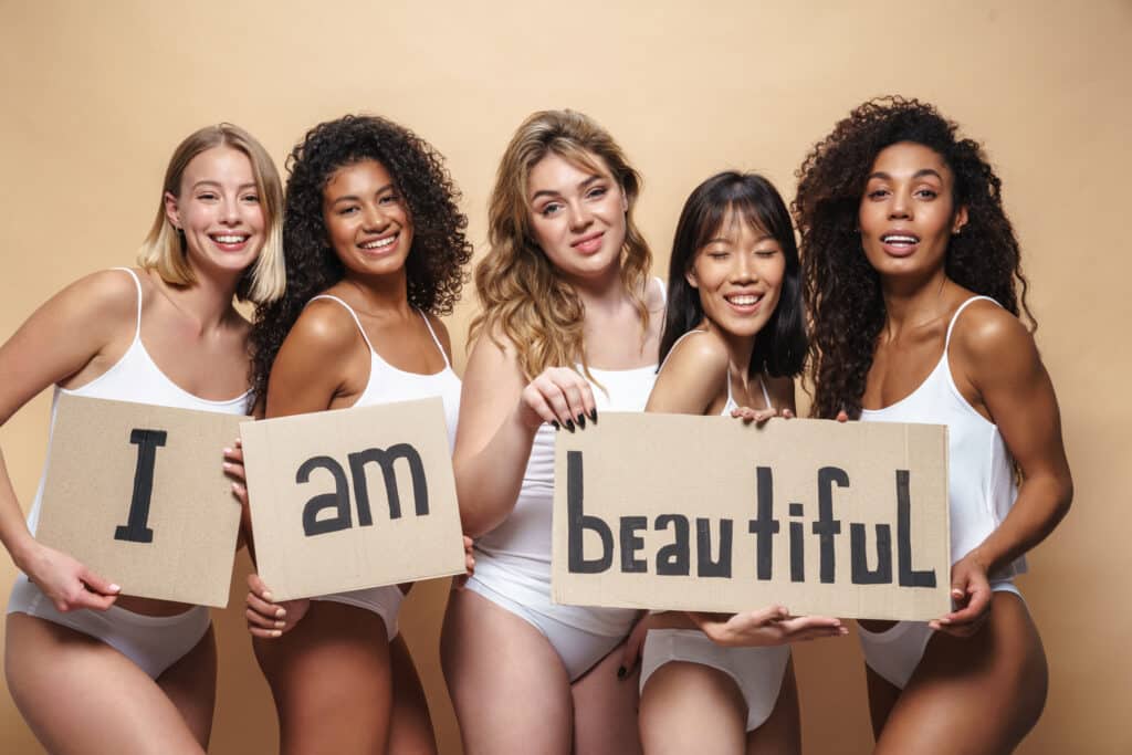 Image of young multinational women smiling and holding placards