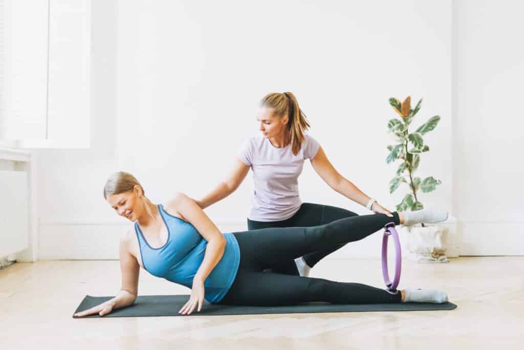 Pregnant woman in sports uniforms with coach doing gymnastic in Pregnant woman in sports uniforms with coach doing gymnastic in