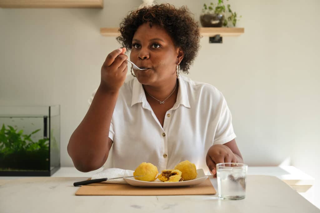 Young cuban woman eating homemade cuban style stuffed potatoes.