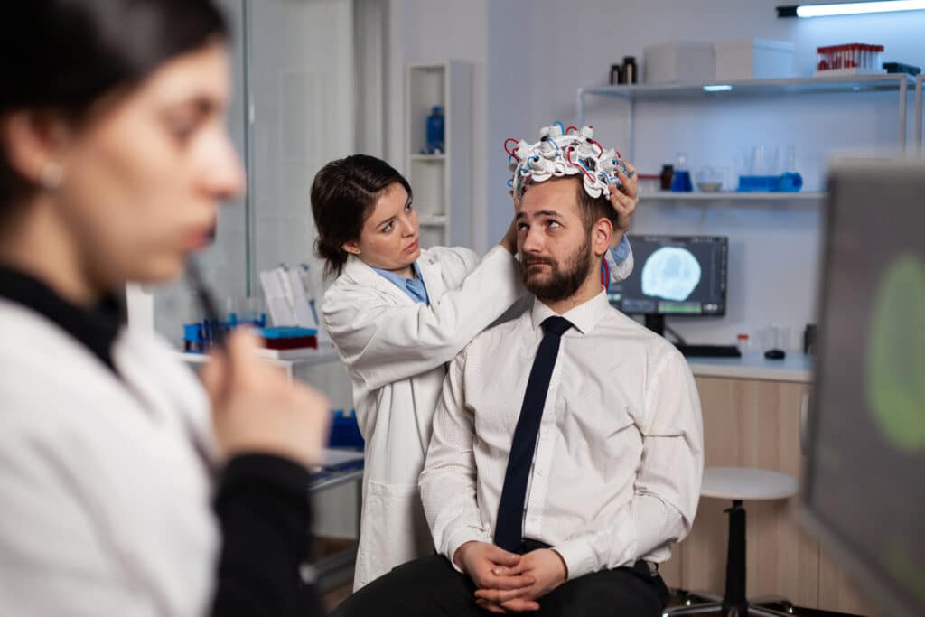 Specialist researcher woman putting eeg headset on man patient analyzing brain evolution