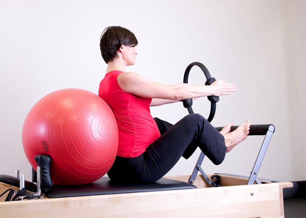 Woman in Red Top Leaning on Red Stability Ball