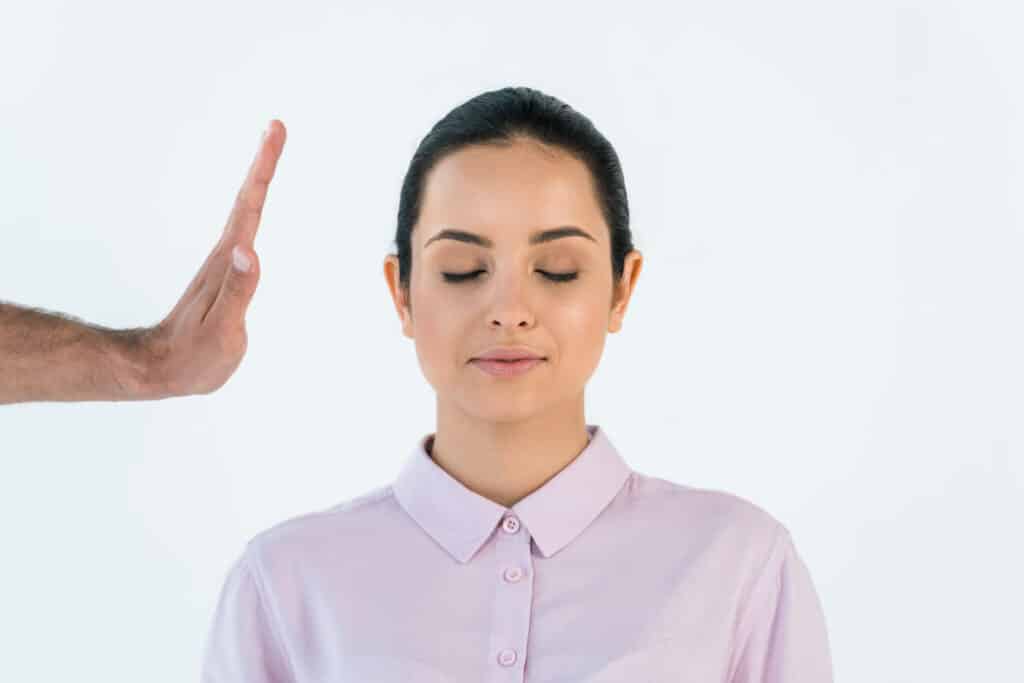 cropped view of healer holding hand near attractive woman with closed eyes isolated on white