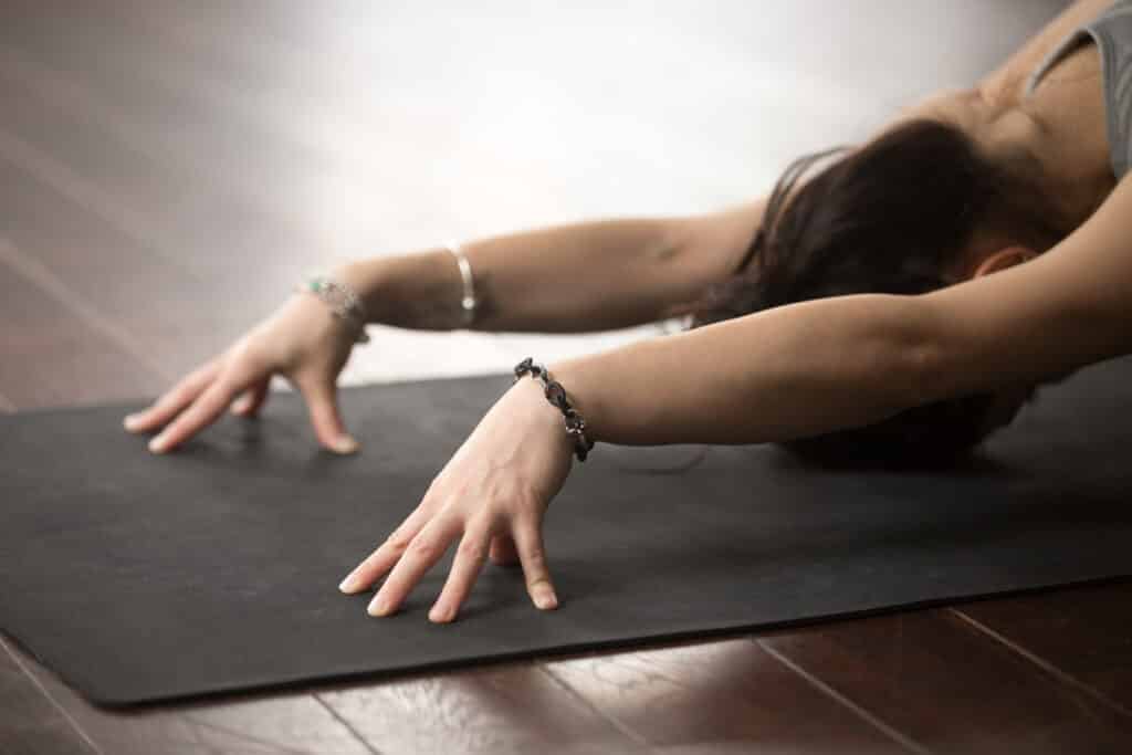 Young beautiful woman in Balasana pose, studio floor background