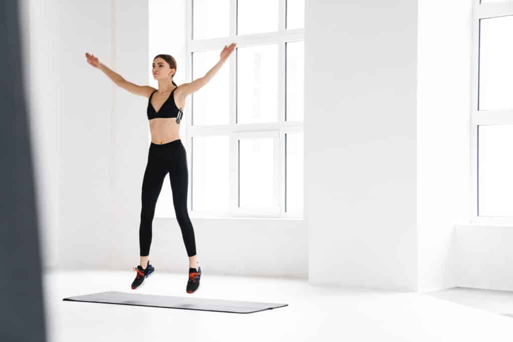 Pleased young sportswoman jumping while working out Pleased young sportswoman jumping while working out