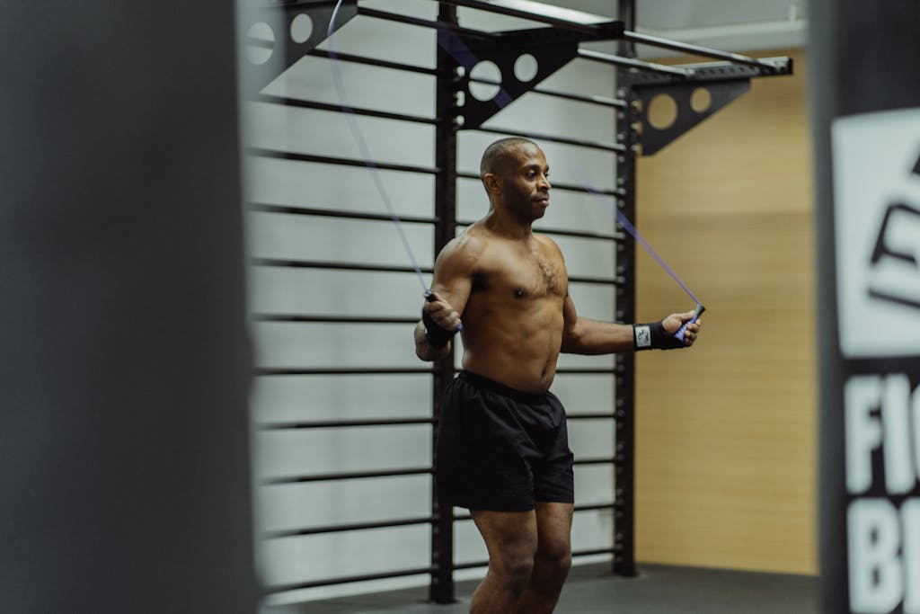 Topless Man in Black Shorts Jumping Beside the Black Metal Bars