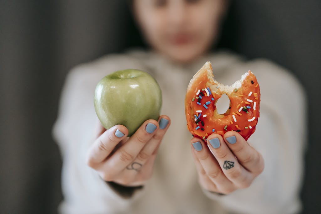 Photo by Andres Ayrton Woman showing apple and bitten doughnut
