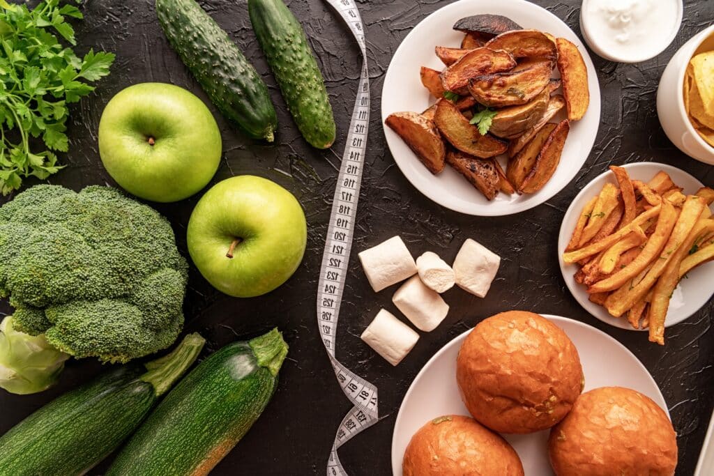 Fruit and vegetables vs sweets and potato fries top view flat lay