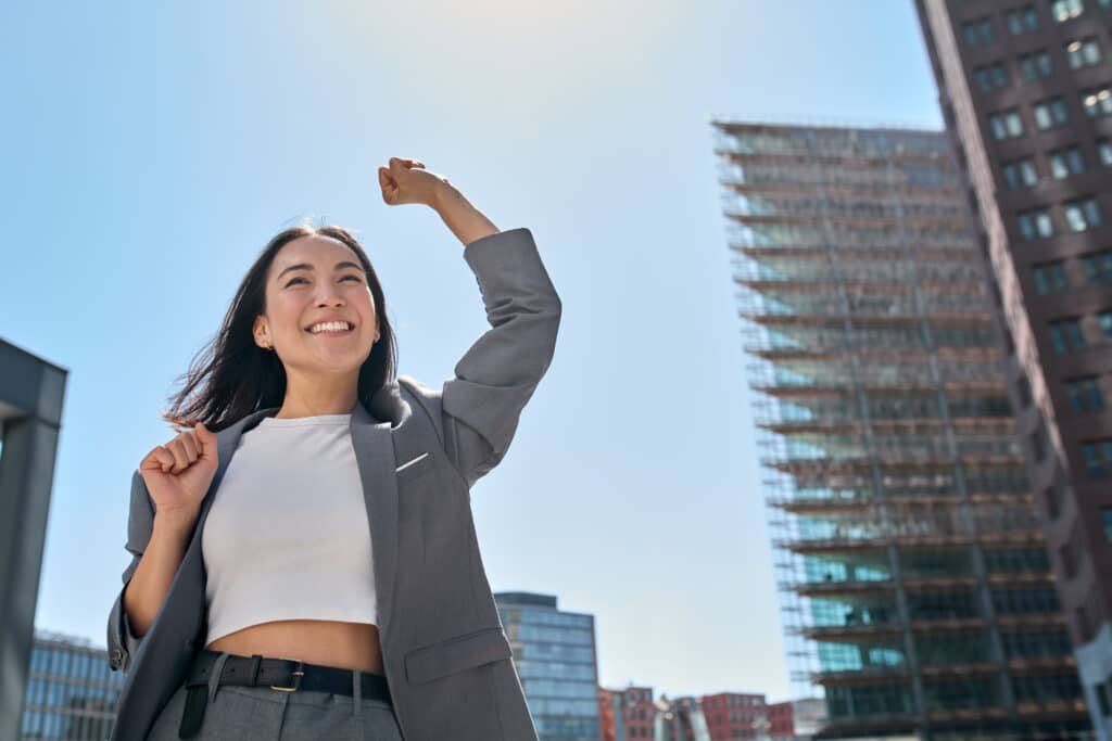 Young excited confident Asian business woman feeling winner in big city.