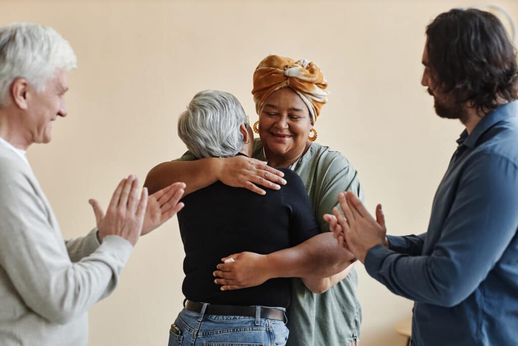Diverse group of elderly people applauding and embracing