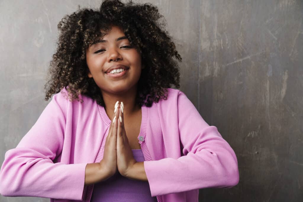 Cheerful african american woman smiling and holding palms together Cheerful african american woman smiling and holding palms together