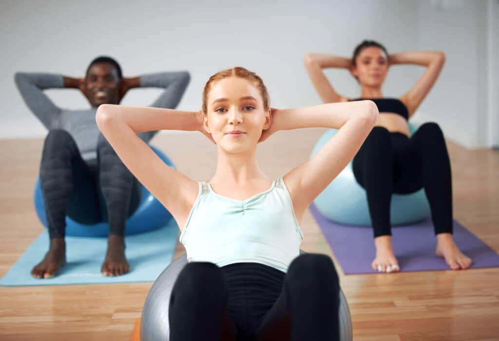Shot of a group of students performing crunches during a pilates class.