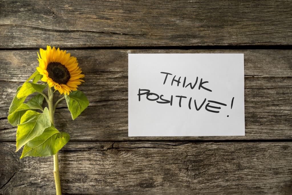 Top view of sunflower lying next to a motivational message Think