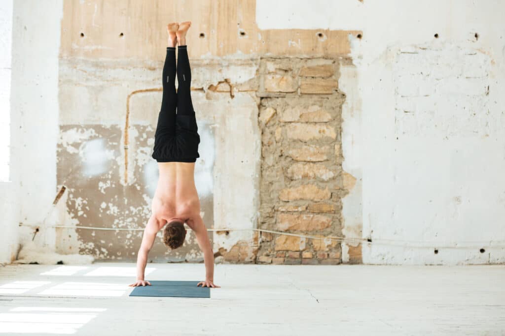 Full length back view of a man practising yoga poses