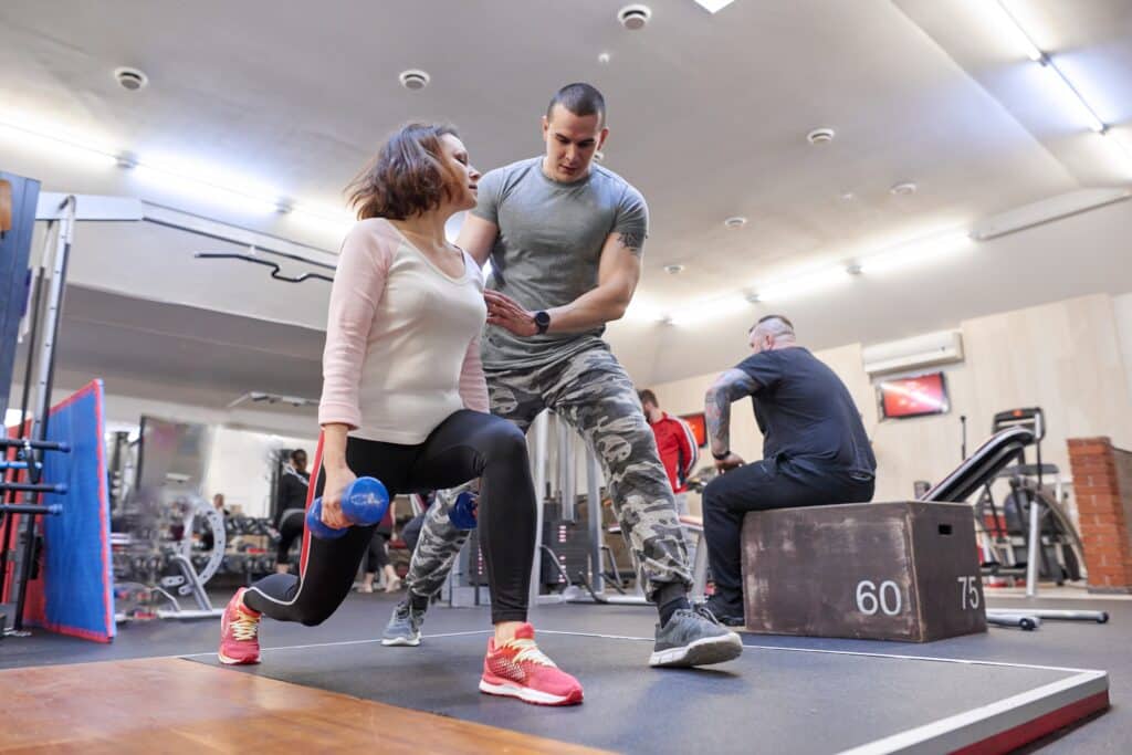 Personal fitness instructor helping summer woman exercising in health club. Personal fitness instructor helping summer woman exercising in health club.