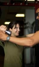 Woman and trainer share a laugh during gym dumbbell training session