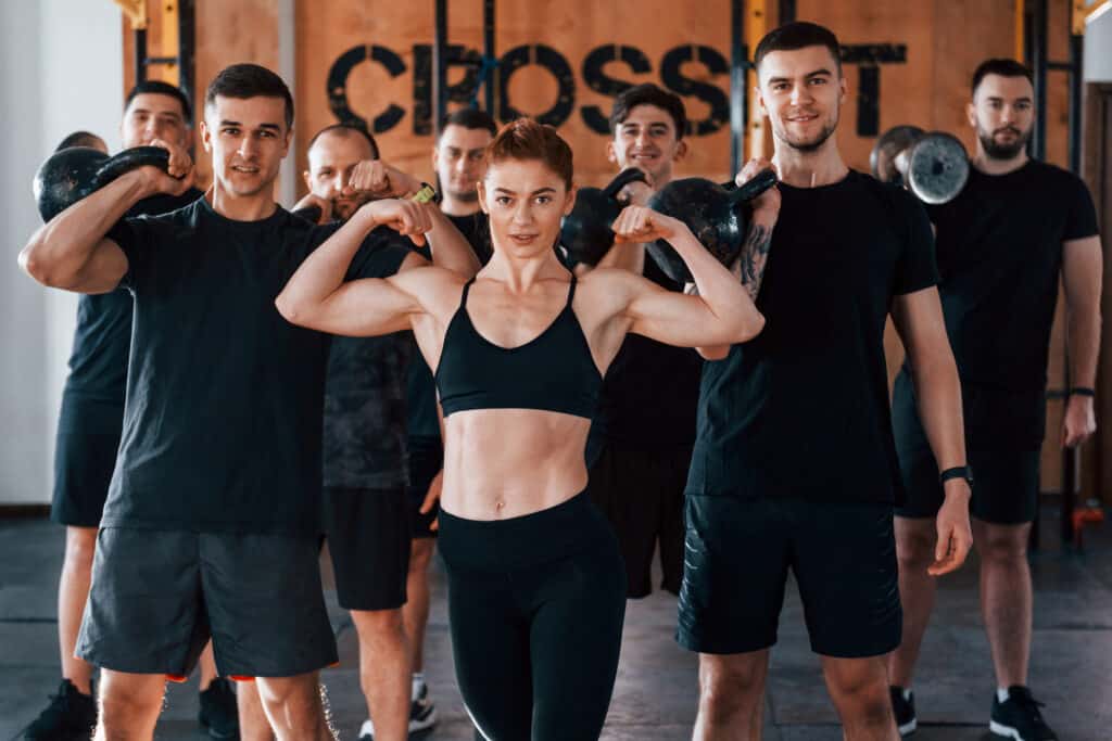 Posing for a camera. Group of young sportive people have crossfit day indoors in gym Posing for a camera. Group of young sportive people have crossfit day indoors in gym