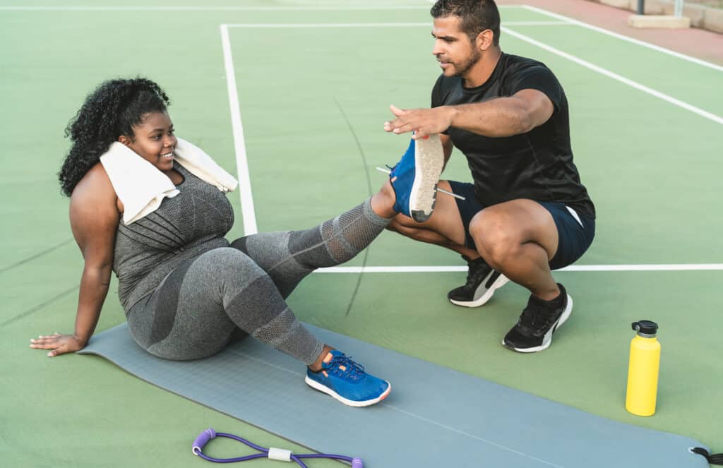 Personal trainer working with curvy woman explaining her the exe