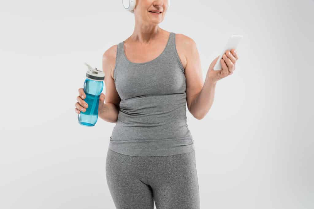 a woman wearing headphones and holding a phone and a water bottle