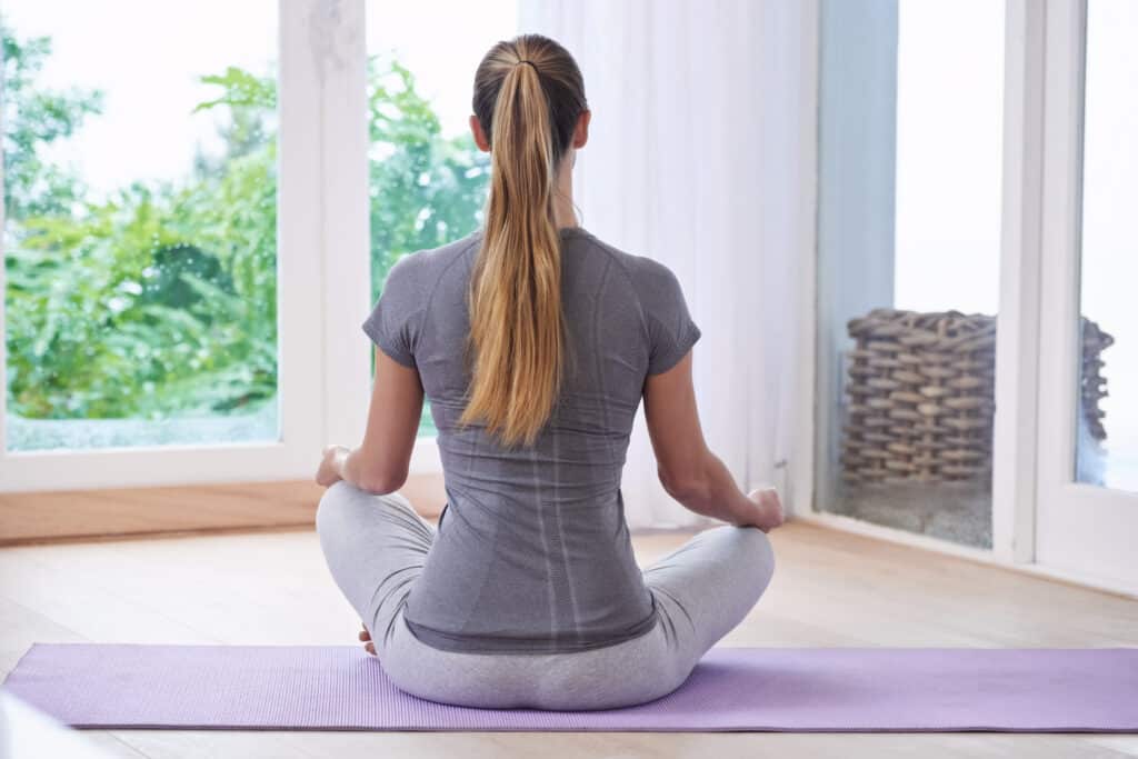 Keep calm and do yoga. A young woman meditating at home