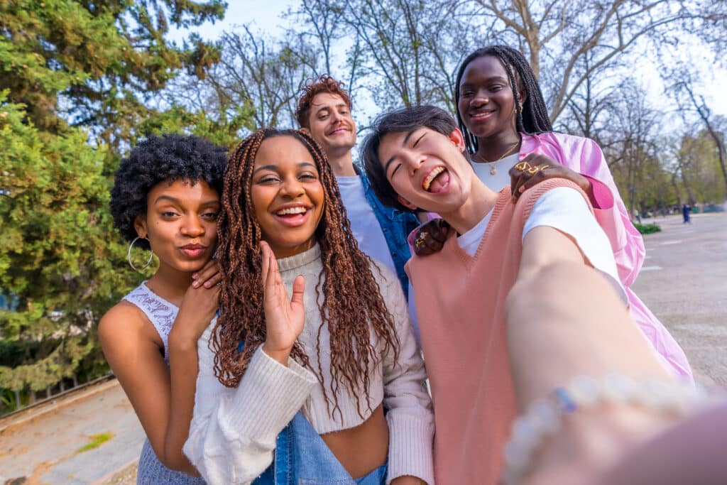 Japanese young man taking selfie with multi-ethnic friends